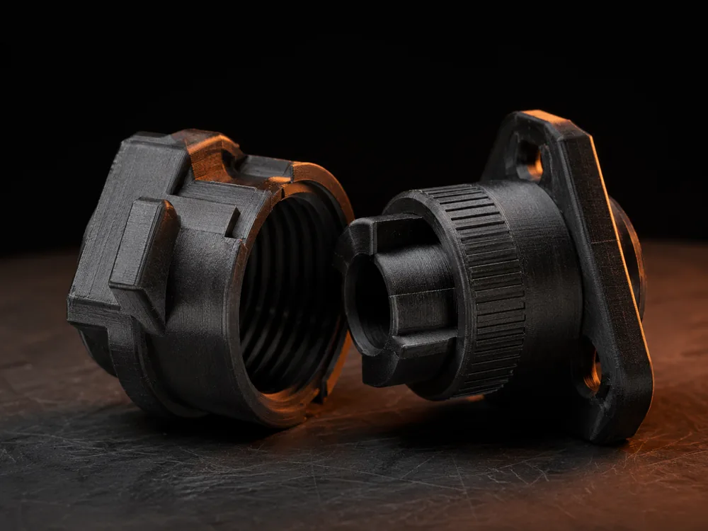 Due componenti meccanici stampati in 3D con filettature e incastri di precisione, parzialmente assemblati